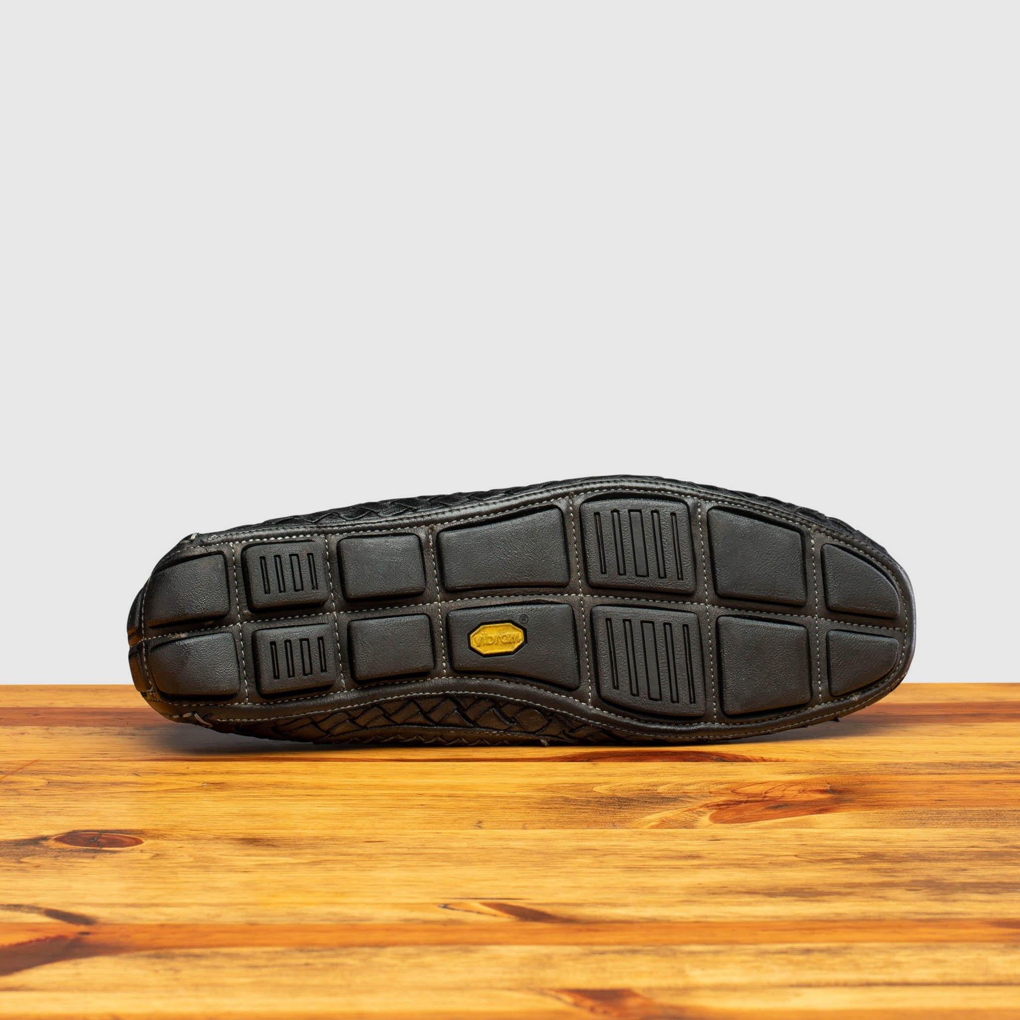 Vibram Outsole of E945 Calzoleria Toscana Black New Rendo Woven Driver on top of a wooden table